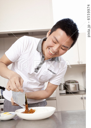 レトルトパックの中身を器にあける男性 6559974