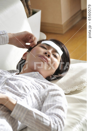 冷却ジェルシートを額に貼って寝る女性 冷却ジェルシートを額に貼って寝る女性 6560079