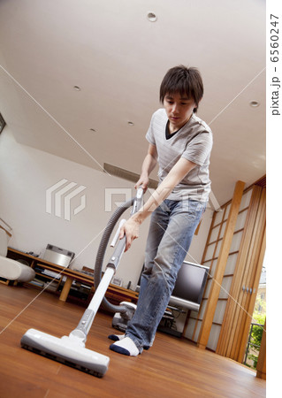 床に掃除機をかける男性 6560247
