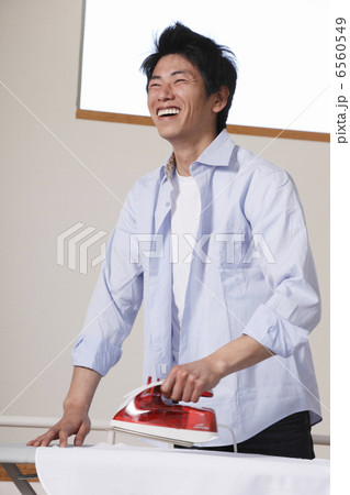 アイロンを持って笑う男性 6560549