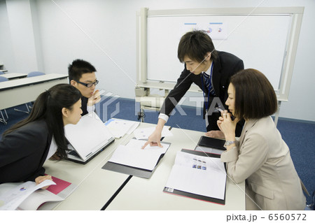 会議をするスーツ姿の男女４人 6560572