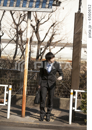 バス亭で時刻表を見るスーツ姿の若い男性 6560652