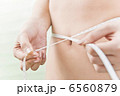 メジャーでウエストサイズを測っている女性 6560879