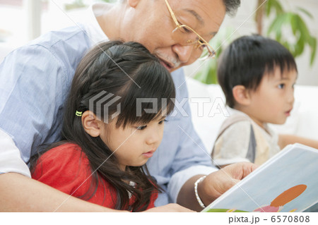 リビングで絵本を読む祖父と孫たち リビングで絵本を読む祖父と孫たち 6570808