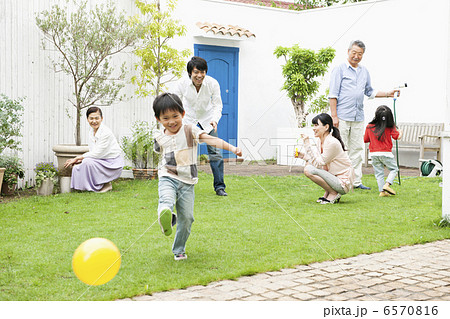 庭で遊ぶ三世代家族の写真素材