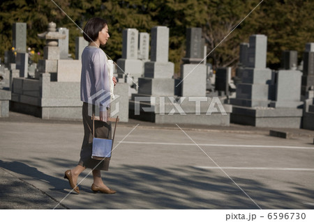 花と水桶を持ち墓地を歩く女性 6596730