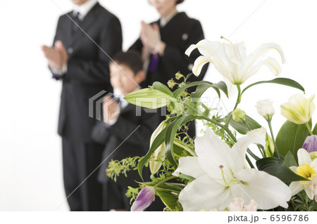 喪服姿で合掌する家族と祭壇の花 6596786