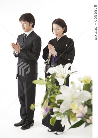 喪服姿で合掌する夫婦と祭壇の花 6596859