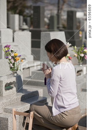 お墓の前で手を合わせる女性 6596869