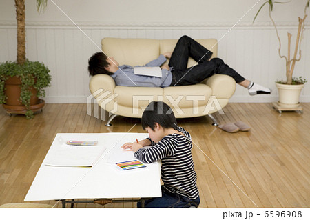 絵を描く男の子とソファで寝転ぶ父の写真素材