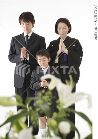 喪服姿で合掌する家族と祭壇の花 6597107
