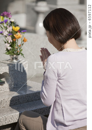 お墓の前で手を合わせる女性の後姿 6597112