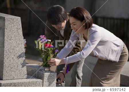 お墓に花を供える夫婦 6597142
