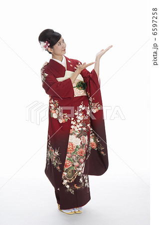 手のひらを上に向ける振袖姿の若い女性 6597258