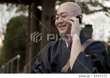 スマートフォンを使用する笑顔の僧侶 スマートフォンを使用する笑顔の僧侶 6597272