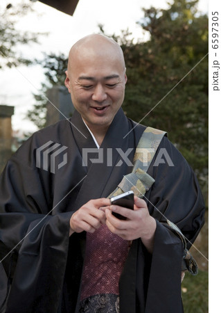 スマートフォンを使用する笑顔の僧侶 スマートフォンを使用する笑顔の僧侶 6597305