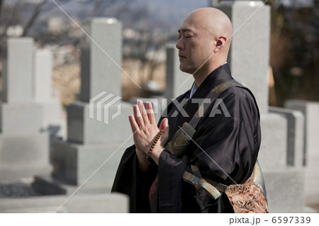 お墓の前で手を合わせる僧侶 6597339
