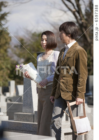 花と水桶を持ち墓地を歩く夫婦 6597388