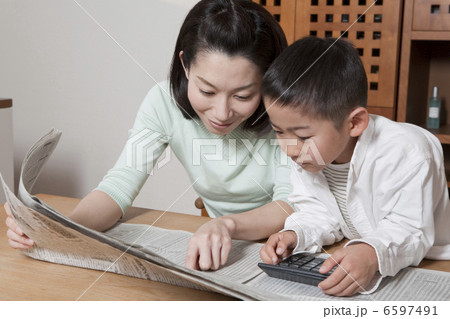 新聞を指差す母親と電卓をたたく男の子 新聞を指差す母親と電卓をたたく男の子 6597491