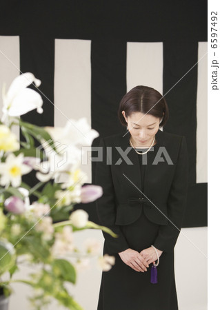 鯨幕の前でおじぎをする喪服姿の女性 6597492