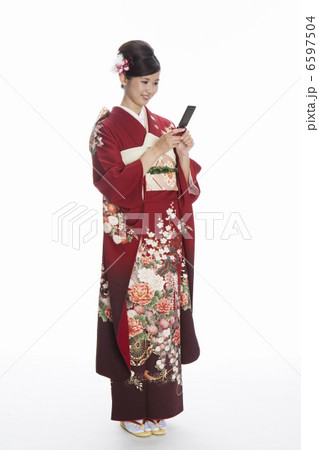 携帯電話を持つ振袖姿の若い女性 6597504