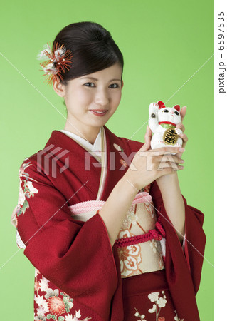 招き猫を持つ振袖姿の若い女性 6597535