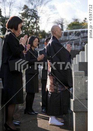 お墓の前で手を合わせる僧侶と喪服姿の遺族 お墓の前で手を合わせる僧侶と喪服姿の遺族 6597712