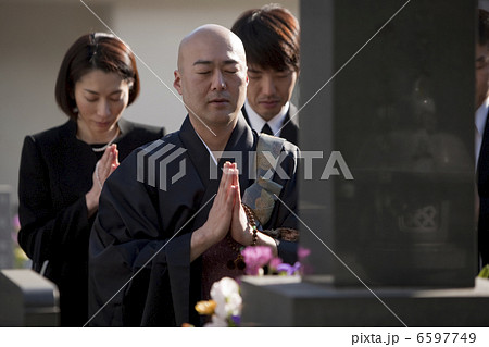 お墓の前で手を合わせる僧侶と喪服姿の遺族 お墓の前で手を合わせる僧侶と喪服姿の遺族 6597749