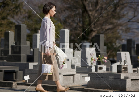 花と水桶を持ち墓地を歩く女性 6597752