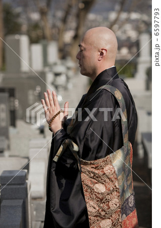 お墓の前で手を合わせる僧侶 6597793