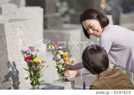 お墓に花を供える夫婦 6597829