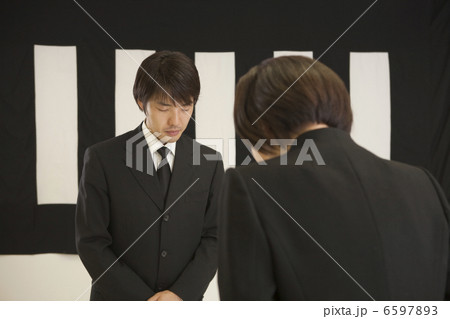 葬儀の受付で挨拶をする喪服姿の男女 6597893