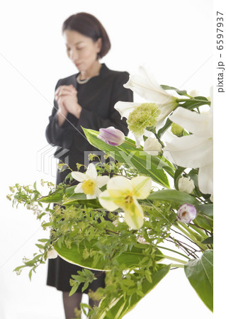手を組んで祈る喪服姿の女性と祭壇の花 6597937