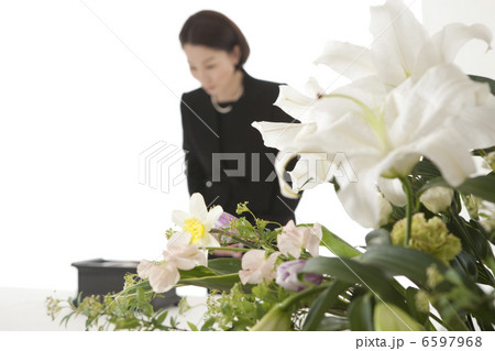 焼香台の前でおじぎをする喪服姿の女性 6597968