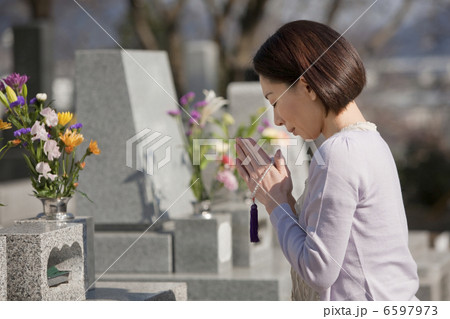 お墓の前で手を合わせる女性 6597973
