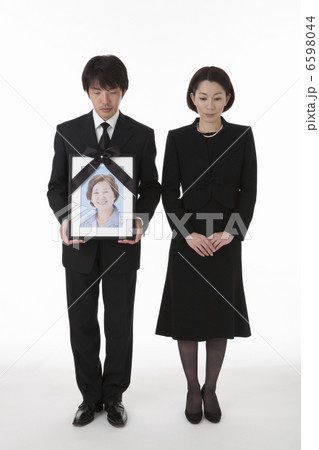 遺影を持って立つ喪服姿の夫婦 正面 6598044