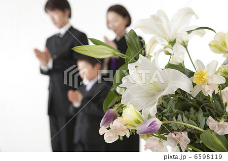 喪服姿で合掌する家族と祭壇の花 6598119