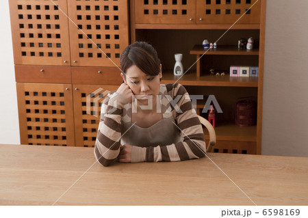 テーブルに肘をついてぼんやりする女性 6598169