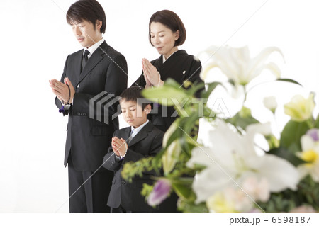 喪服姿で合掌する家族と祭壇の花 6598187