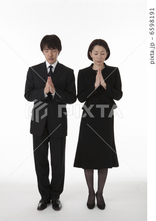 目を閉じ合掌する喪服姿の夫婦 正面 6598191