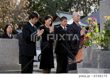 お墓の前で手を合わせる僧侶と喪服姿の遺族 お墓の前で手を合わせる僧侶と喪服姿の遺族 6598270