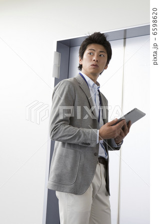 タブレットPCを持って立っている男性 6598620