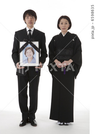 遺影を持って立つ喪服姿の夫婦 正面 6598635