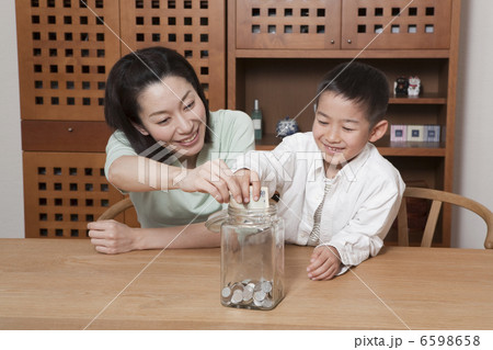 千円札を貯金する男の子と母親 6598658