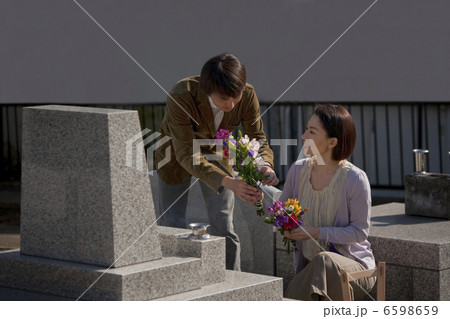 お墓に花を供える夫婦 6598659