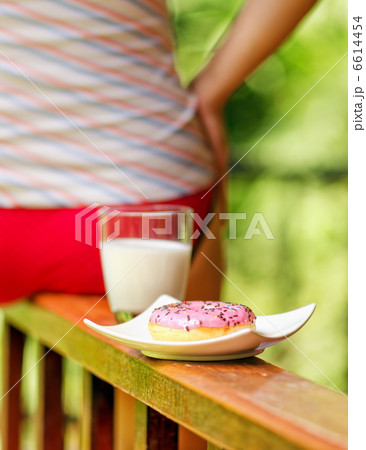Young woman sitting on terrace with milk and donut Young woman sitting on terrace with milk and donut 6614454