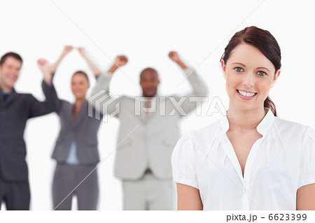 Smiling saleswoman with cheering associates behind her Smiling saleswoman with cheering associates behind her 6623399