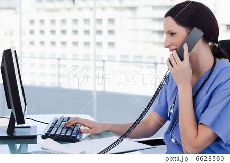 Female doctor on the phone while using a monitor Female doctor on the phone while using a monitor 6623560