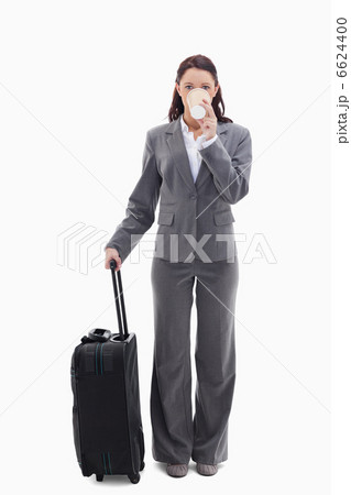 Businesswoman with a suitcase drinking a coffee Businesswoman with a suitcase drinking a coffee 6624400