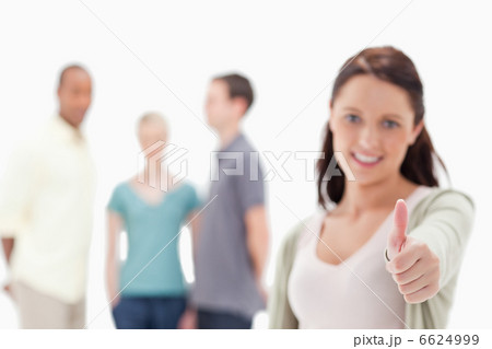 Close-up of a woman giving the thumbs-up with friends 6624999
